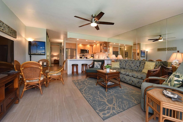 living room featuring ceiling fan, sink, and light hardwood / wood-style floors