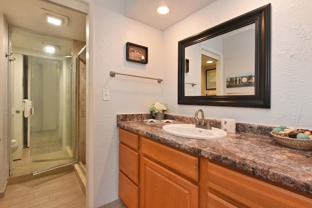 bathroom with a shower with door, toilet, and vanity