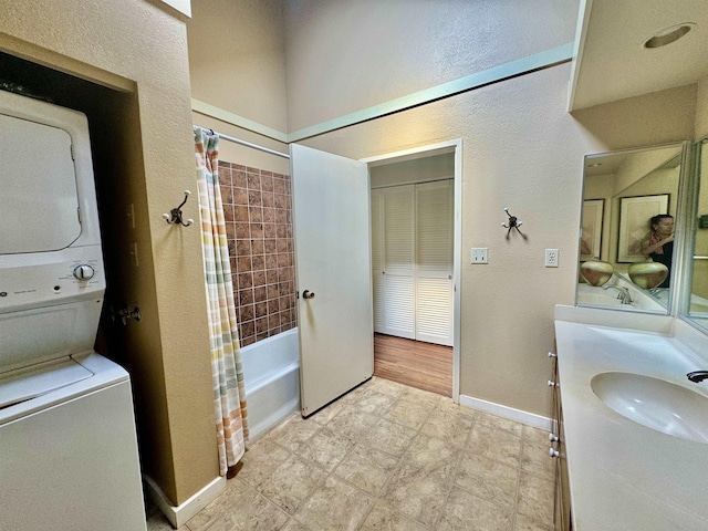 bathroom with vanity, shower / bath combo with shower curtain, and stacked washer / dryer