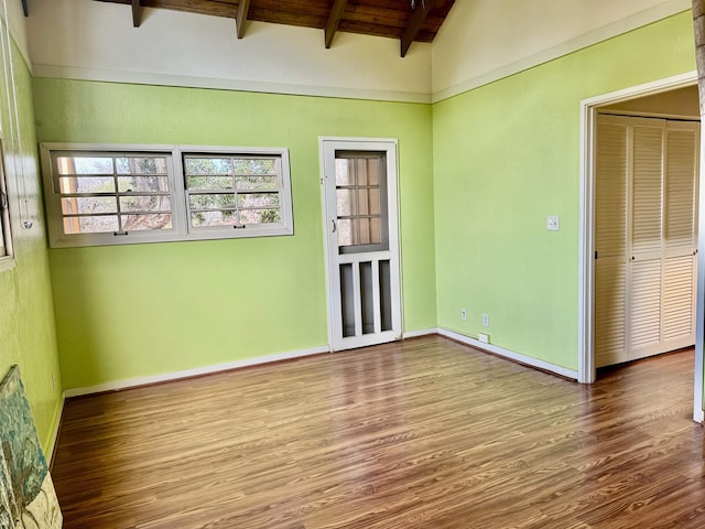 empty room featuring lofted ceiling with beams, hardwood / wood-style floors, and wood ceiling