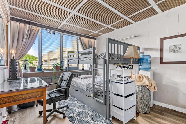 bedroom with concrete block wall and wood finished floors