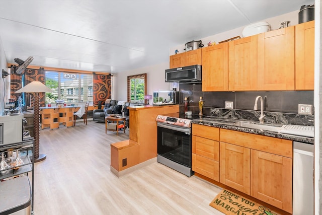 kitchen with stainless steel appliances, backsplash, light wood-style floors, open floor plan, and a sink