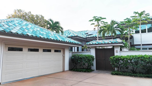 view of front of home featuring a garage, a tile roof, driveway, and stucco siding