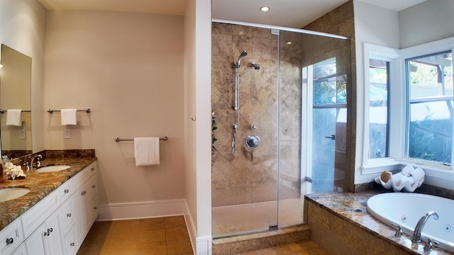 bathroom featuring double vanity, a stall shower, baseboards, a jetted tub, and a sink