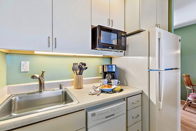 kitchen featuring white appliances, light hardwood / wood-style floors, white cabinetry, and sink