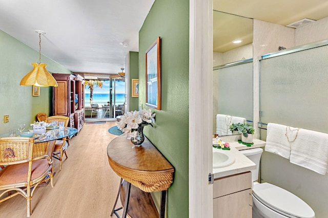 bathroom with vanity, wood-type flooring, a shower with shower door, and toilet