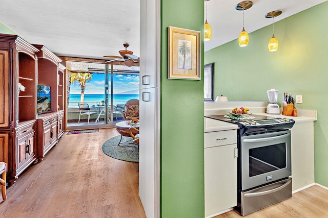 kitchen with light wood-type flooring, decorative light fixtures, stainless steel electric stove, and ceiling fan