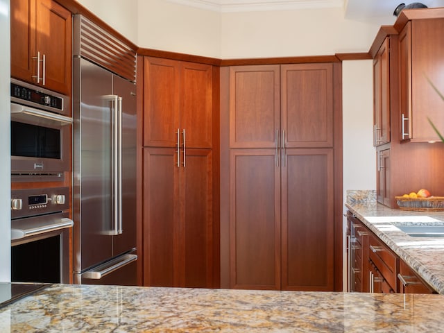 kitchen featuring light stone countertops, stainless steel appliances, and crown molding