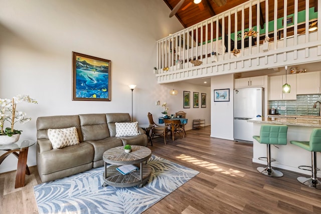 living room featuring high vaulted ceiling, beam ceiling, sink, and dark hardwood / wood-style floors