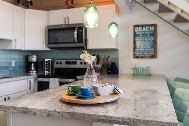 kitchen featuring white cabinets, backsplash, light stone countertops, stainless steel appliances, and kitchen peninsula