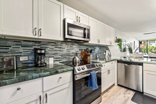 kitchen featuring decorative backsplash, white cabinetry, appliances with stainless steel finishes, and dark stone counters