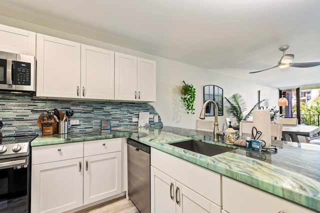 kitchen with sink, stainless steel appliances, white cabinetry, and light stone countertops
