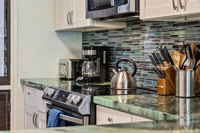 kitchen with white cabinetry, appliances with stainless steel finishes, dark stone counters, and tasteful backsplash