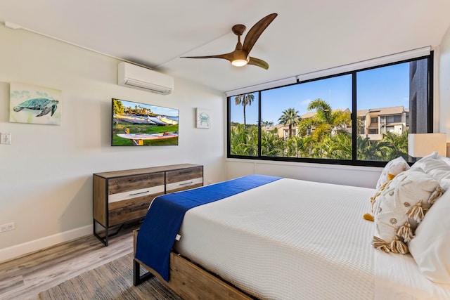 bedroom with ceiling fan, hardwood / wood-style flooring, and a wall mounted AC