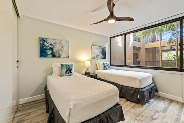 bedroom with light wood-type flooring, expansive windows, and ceiling fan