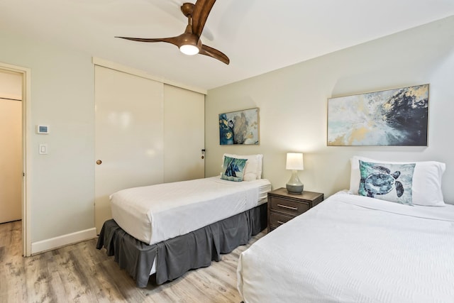 bedroom with light wood-type flooring, ceiling fan, and a closet