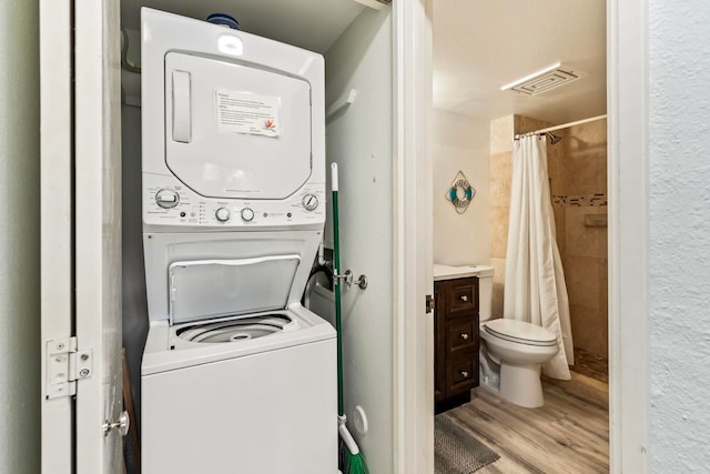 washroom featuring stacked washer and clothes dryer and light hardwood / wood-style flooring