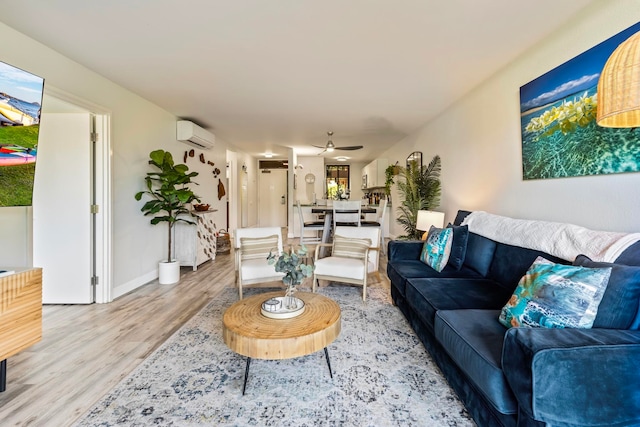 living room featuring a wall mounted AC, light hardwood / wood-style flooring, and ceiling fan