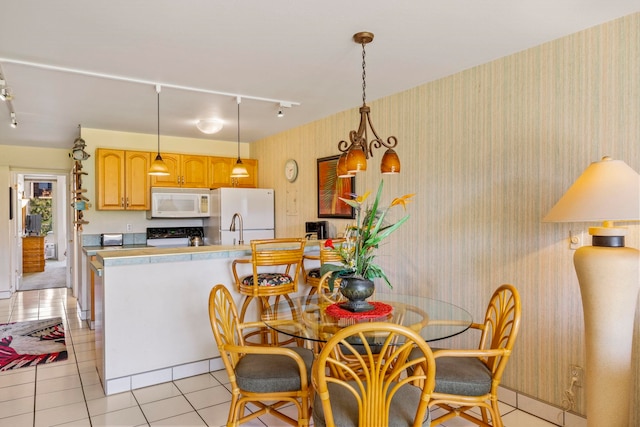 tiled dining area featuring rail lighting and a chandelier