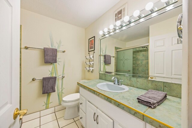 bathroom featuring tile patterned floors, vanity, an enclosed shower, and toilet