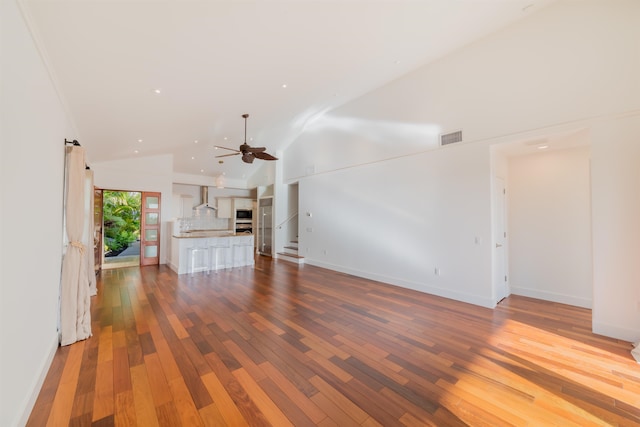 unfurnished living room with ceiling fan, wood-type flooring, and high vaulted ceiling