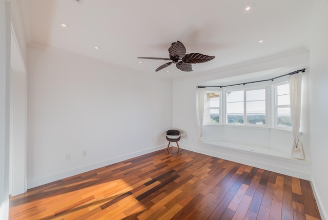 empty room featuring ceiling fan, crown molding, and dark wood-type flooring