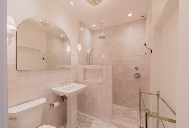 bathroom with tiled shower, toilet, and tile walls