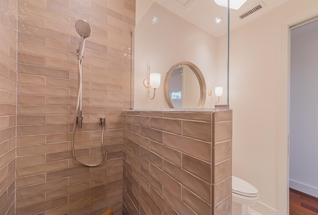 bathroom with toilet, hardwood / wood-style floors, and a tile shower