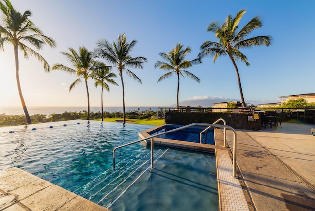 view of swimming pool featuring a water view and a jacuzzi