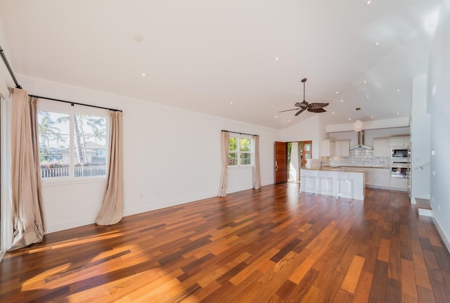 unfurnished living room featuring a healthy amount of sunlight, dark hardwood / wood-style flooring, crown molding, and vaulted ceiling