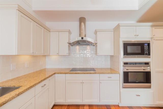 kitchen with exhaust hood, backsplash, light hardwood / wood-style flooring, and black appliances