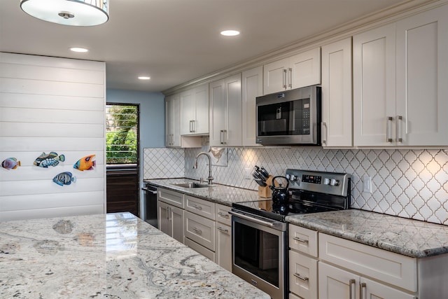 kitchen with light stone counters, a sink, decorative backsplash, and stainless steel appliances