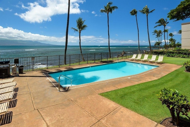 community pool with fence, area for grilling, a water view, a lawn, and a patio