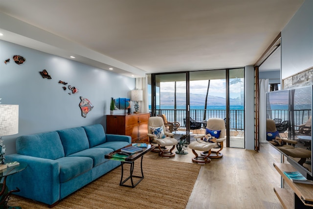 living area featuring a water view, floor to ceiling windows, and wood finished floors