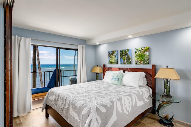 bedroom with access to outside, recessed lighting, a water view, and wood finished floors