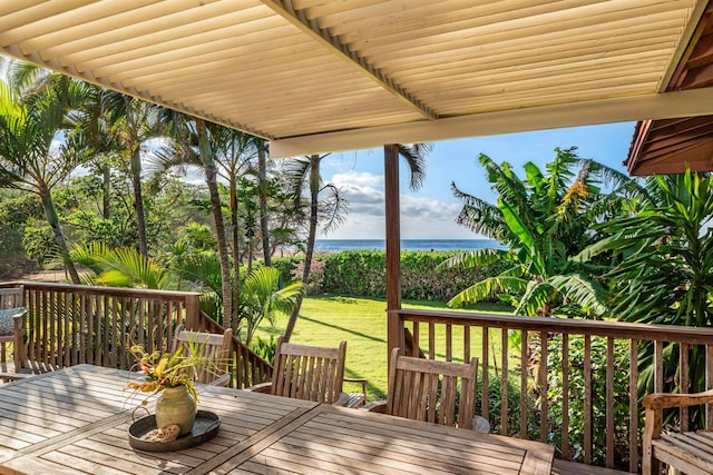 wooden terrace featuring outdoor dining space, a water view, and a yard