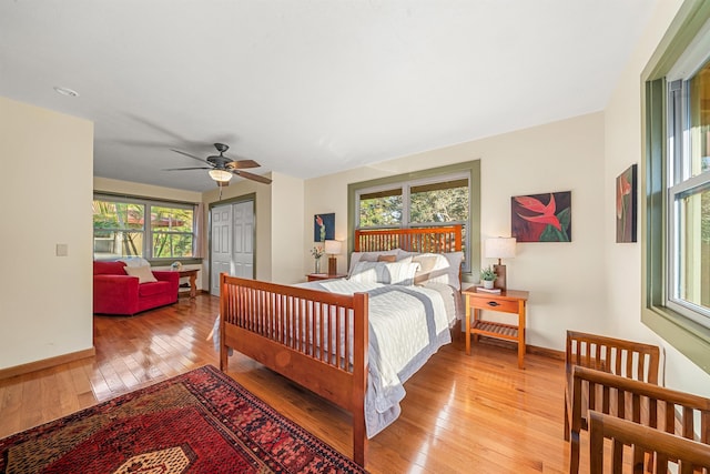 bedroom with a closet, ceiling fan, light wood-style flooring, and baseboards