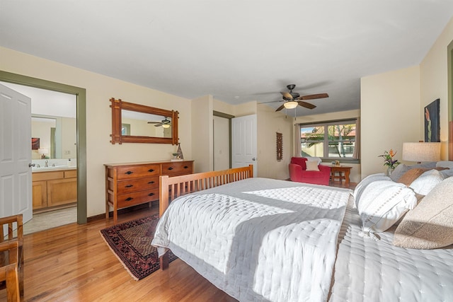 bedroom with light wood-style floors, a sink, ceiling fan, and ensuite bathroom