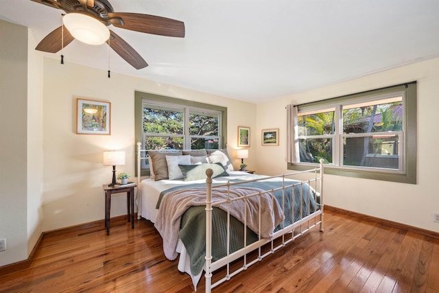 bedroom featuring wood-type flooring, multiple windows, and baseboards