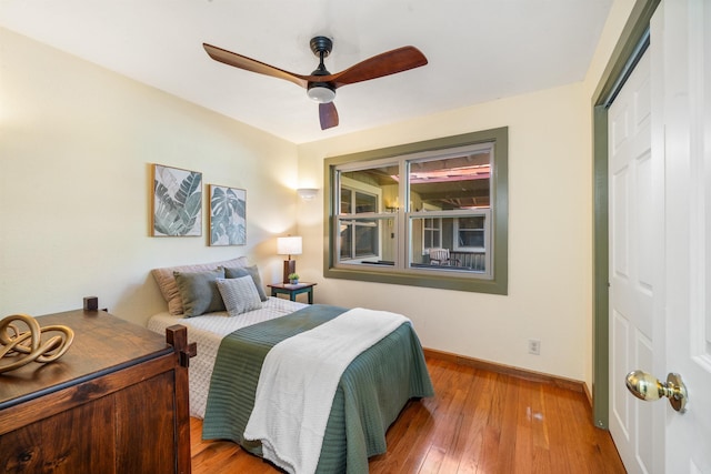 bedroom with hardwood / wood-style floors, a closet, a ceiling fan, and baseboards