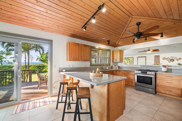 kitchen with light tile patterned floors, light countertops, stainless steel gas range oven, and wood ceiling