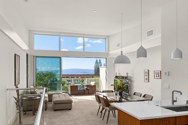 interior space with light carpet, a towering ceiling, sink, decorative light fixtures, and a mountain view