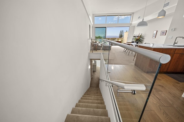 staircase with hardwood / wood-style flooring, a towering ceiling, and sink