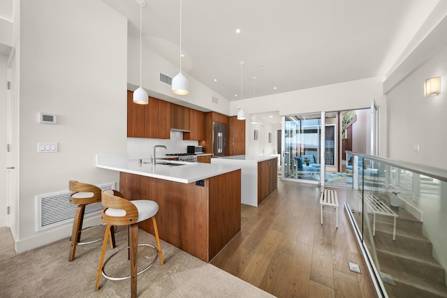 kitchen with a kitchen breakfast bar, tasteful backsplash, kitchen peninsula, decorative light fixtures, and light wood-type flooring