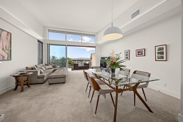 carpeted dining area featuring a towering ceiling