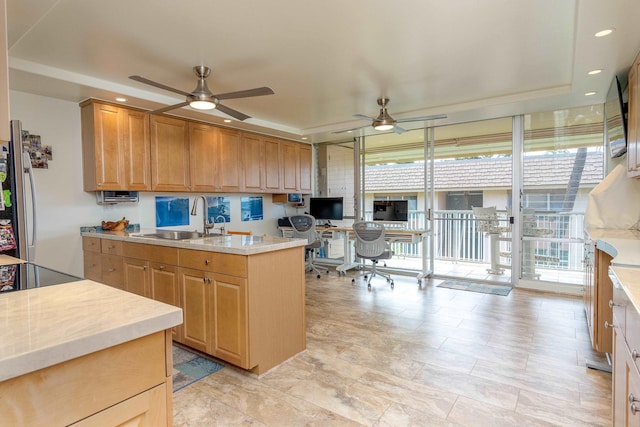 kitchen featuring stainless steel refrigerator, sink, expansive windows, ceiling fan, and a raised ceiling