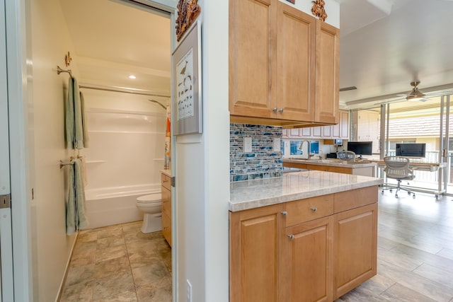 kitchen featuring decorative backsplash, light stone countertops, and ceiling fan