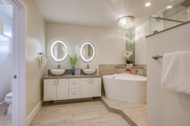 bathroom with toilet, a sink, a freestanding bath, and double vanity