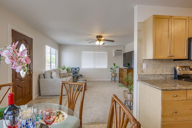 dining space with an AC wall unit, light carpet, ceiling fan, and baseboards