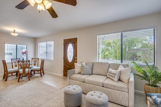 living area with ceiling fan, light tile patterned flooring, and baseboards